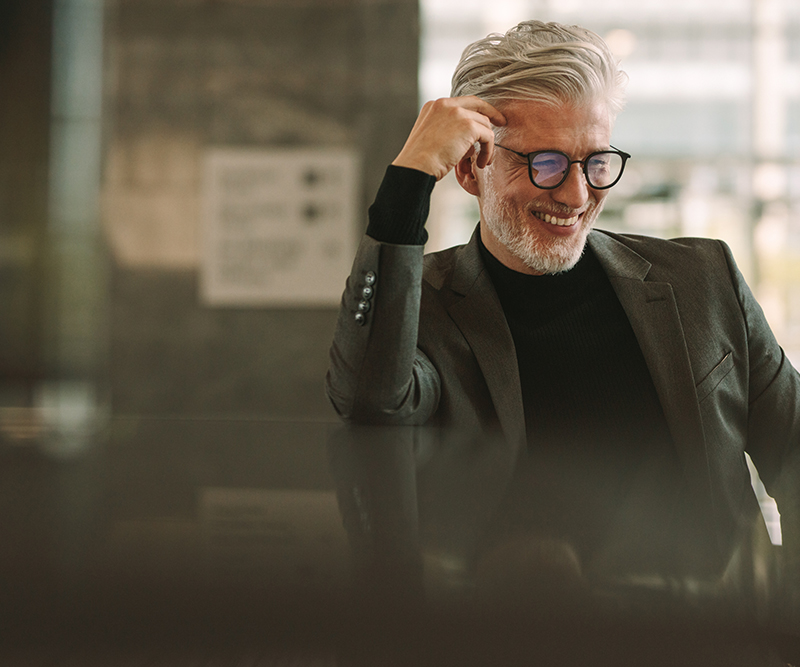 Man standing by a modern kitchen counter, holding a white coffee mug.