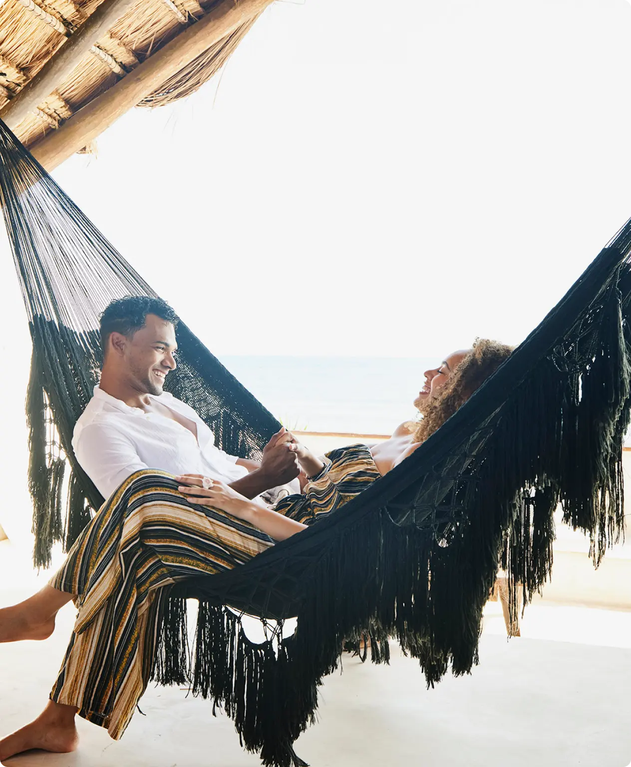 Smiling couple relaxes together in a black hammock.