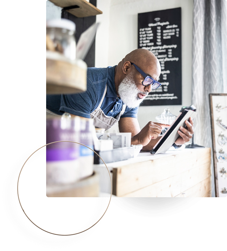 Business owner with glasses and apron reviewing information on a tablet.