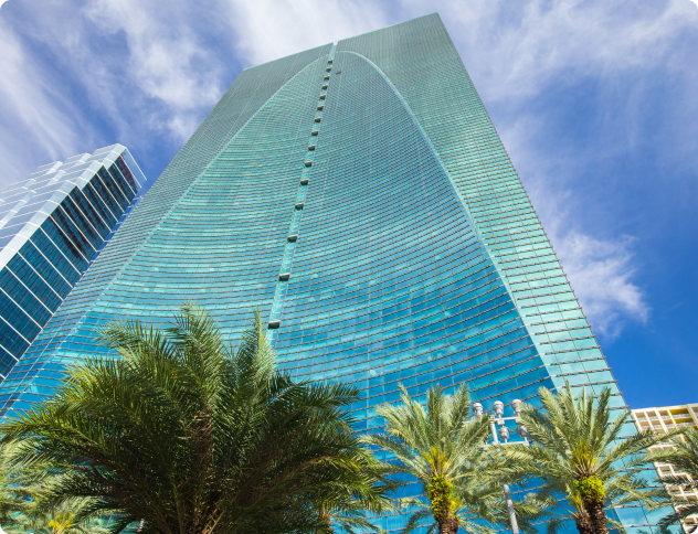Tall glass skyscraper with palm trees.