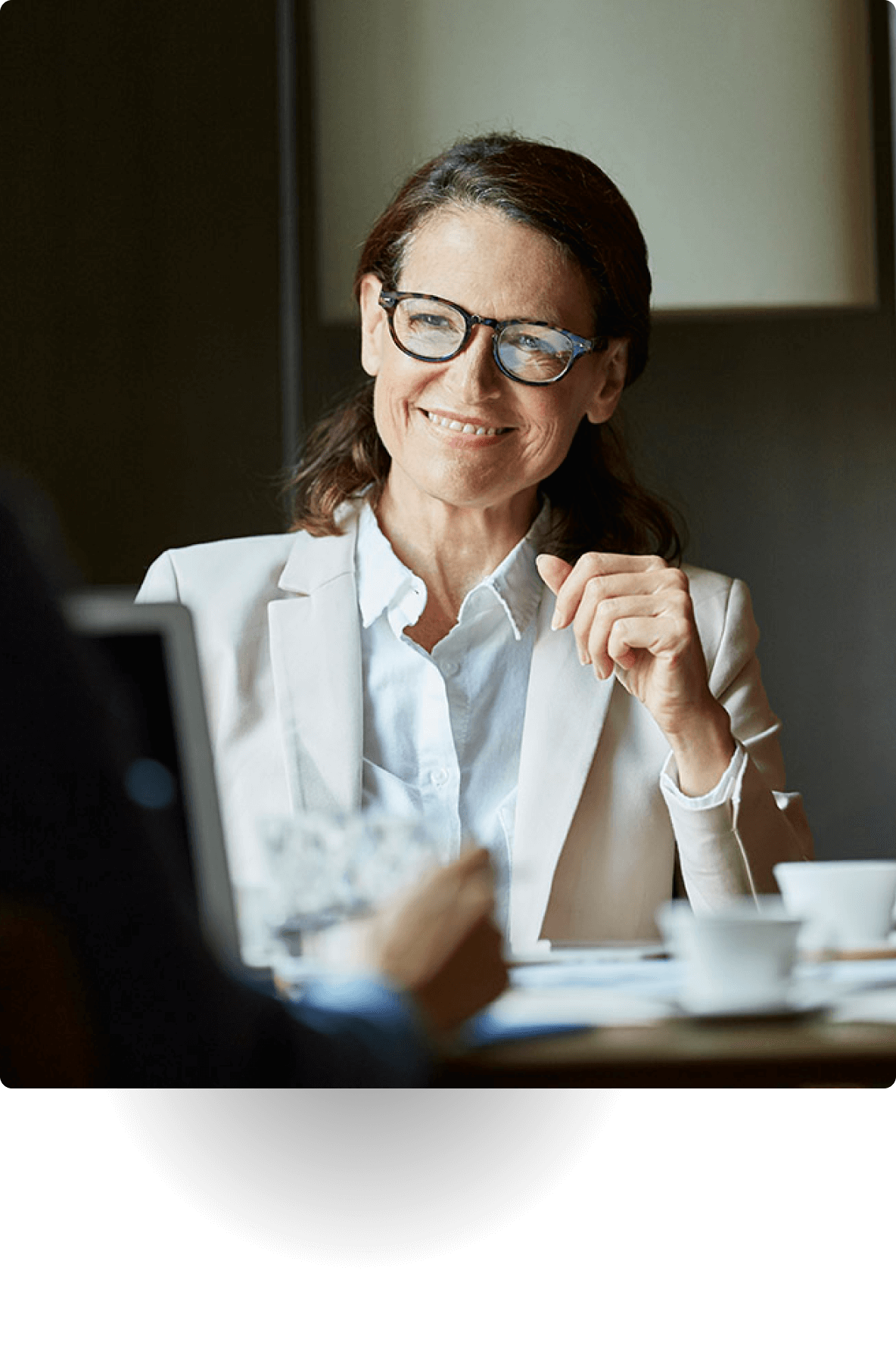 Professional woman in glasses and blazer smiling during a meeting.