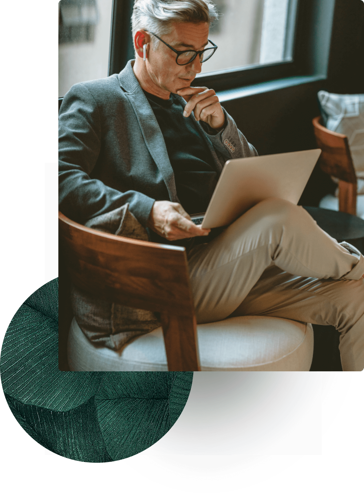 Man with glasses using laptop while sitting indoors.