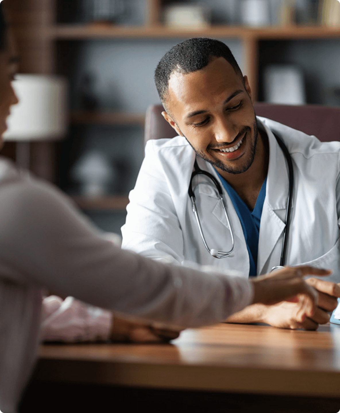 Smiling man in a white coat meeting with a patient.