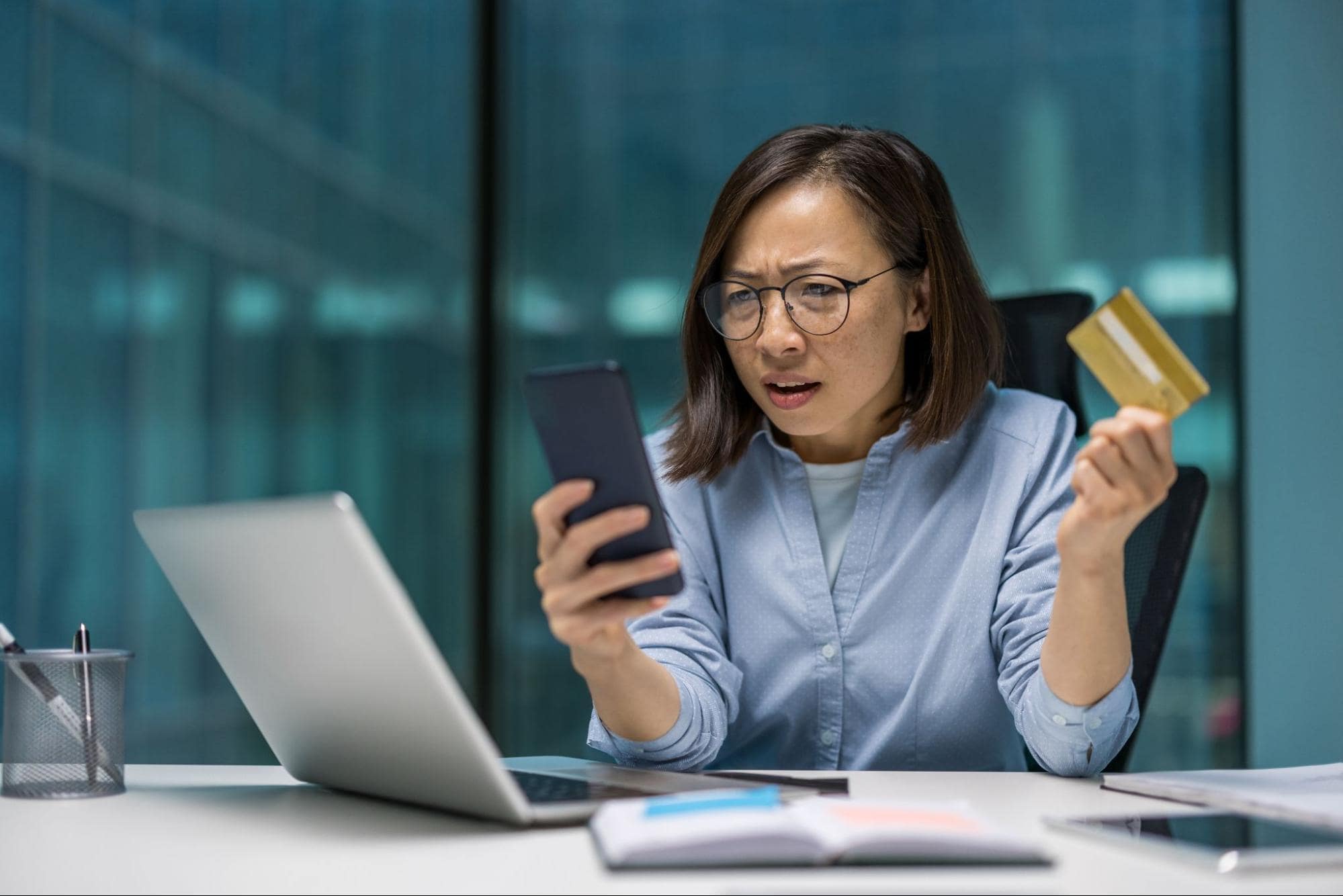 A shocked woman checks her bank account after falling for a scam