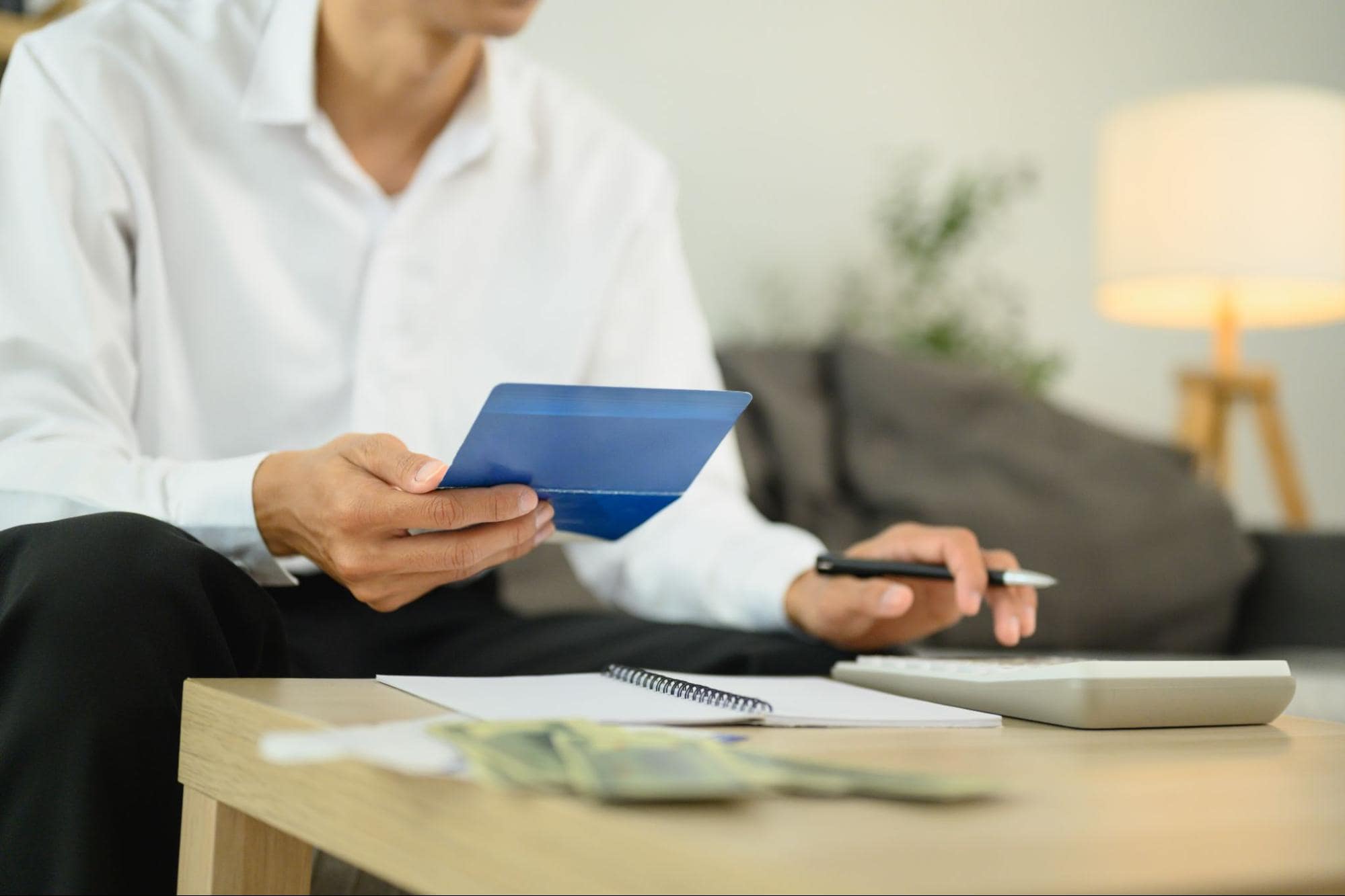 A man using a calculator while reviewing financial documents and bank account information for fraud prevention