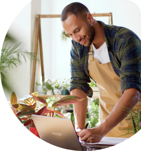 Small business owner working on a laptop in a plant shop, exploring SBA loan options